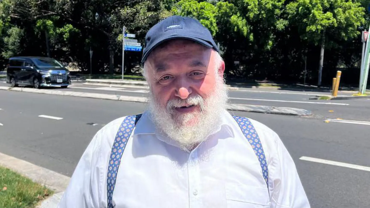ABC News: Danuta Kozaki An elderly man with a bushy white beard and a baseball cap smiles at the camera